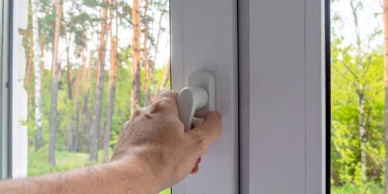 mano cerrando una ventana de doble acristalamiento